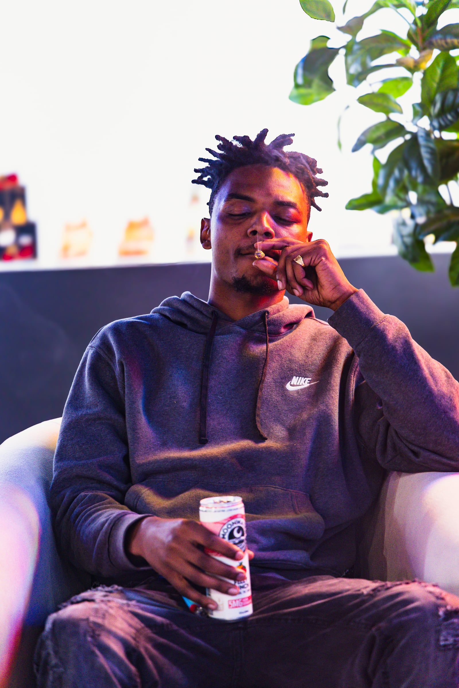 Man in Nike hoodie relaxing with beverage
