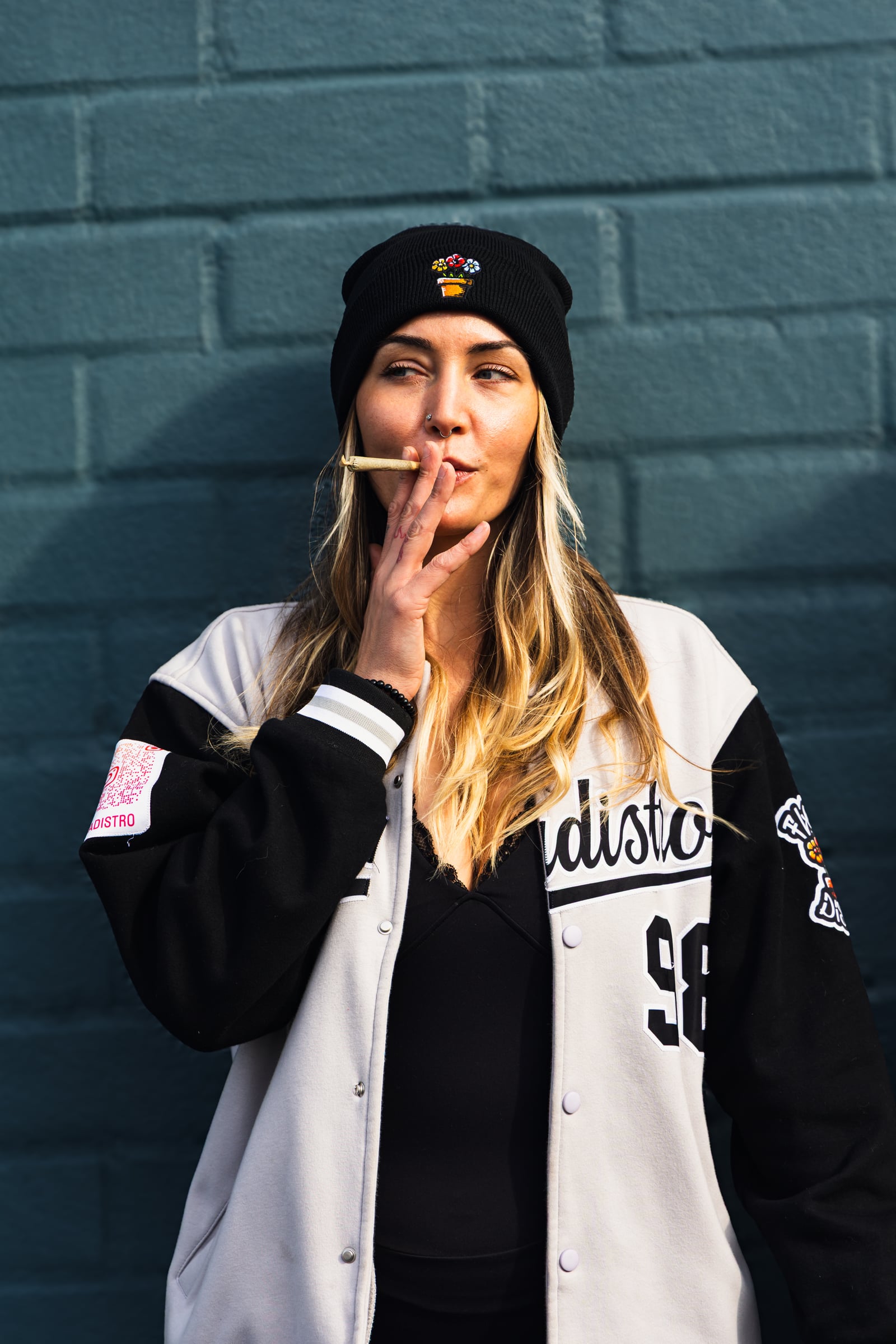 Woman in baseball jersey by blue brick