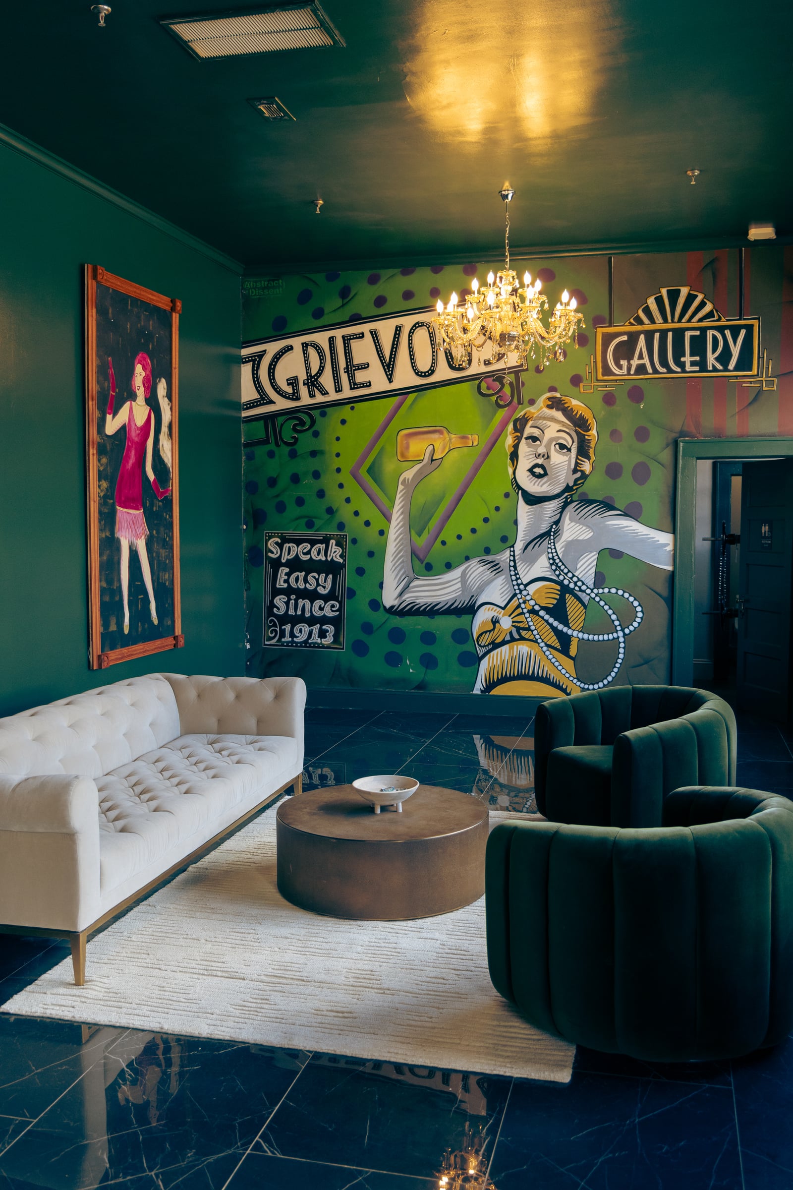 Tufted sofa with velvet chairs and mural